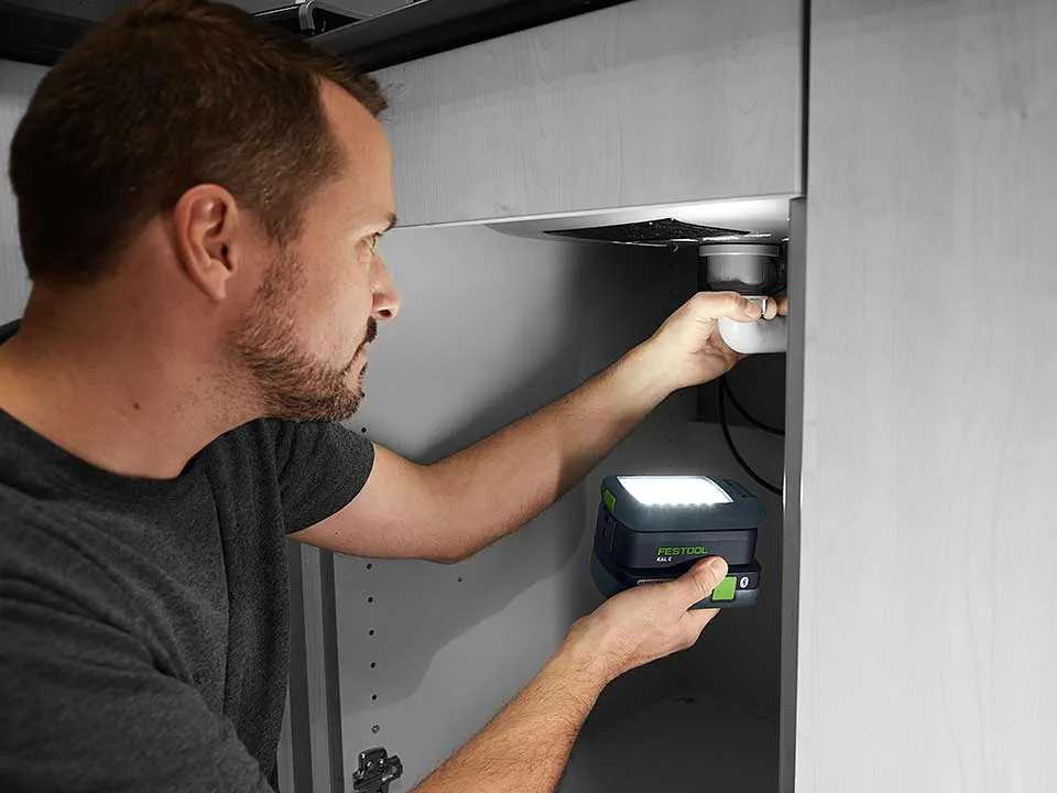 Mies valaisee pesualtaan liitäntää SYSLITE KAL 2:lla.