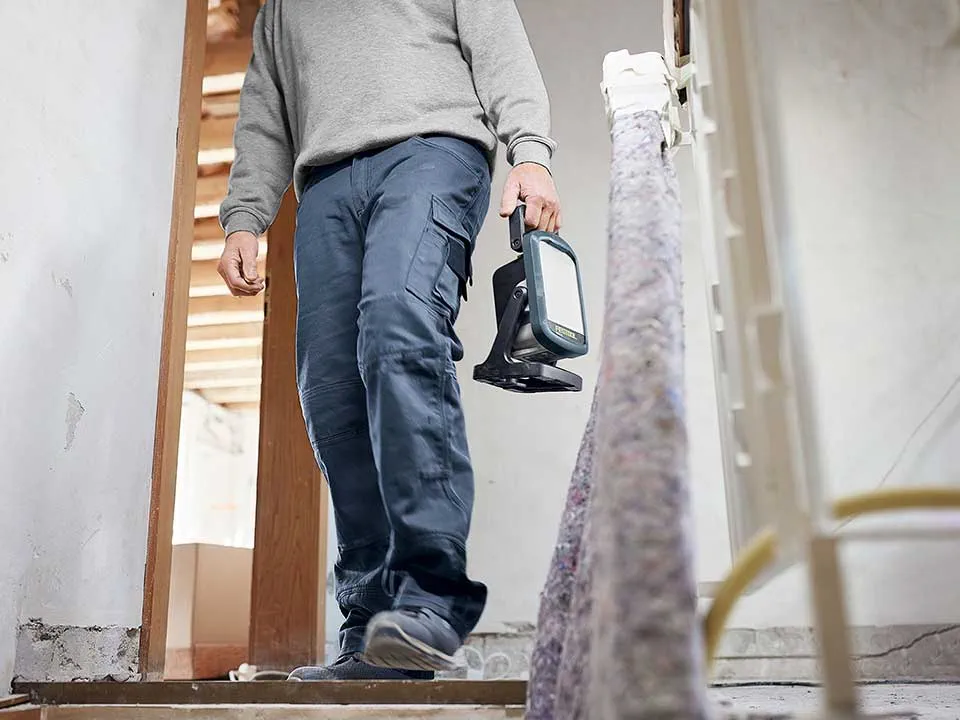 Käsityöläinen kantaa rakennustyövalaisin